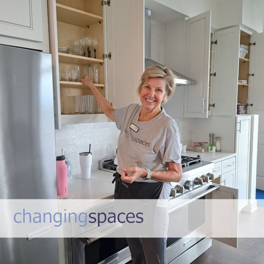 ChangingSpaces team member putting glassware away in kitchen cabinets while unpacking at a new home