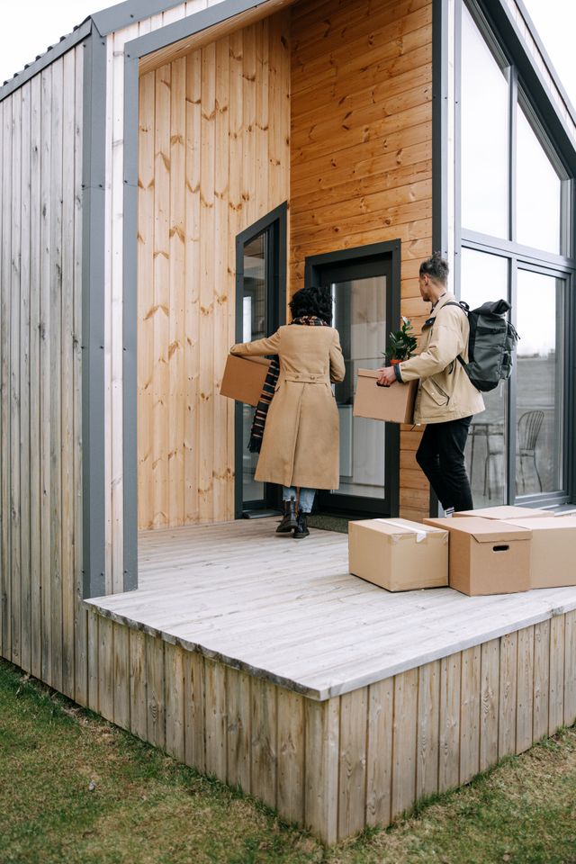 Couple carrying moving boxes into a smaller home during a downsizing move